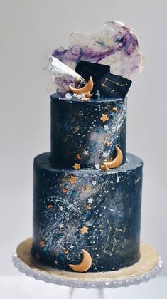 a three tiered black cake with gold stars and moon decorations