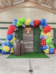 an arch made out of balloons and grass with the number two on it in front of a door