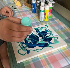 a person is painting on a canvas with blue paint