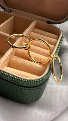 an open green case with two gold rings in it on a white tablecloth background