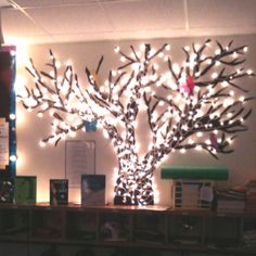 a lighted tree is in the middle of a room with bookshelves and desks