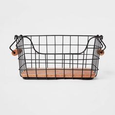 a black wire basket with wooden handles on a white background, it is also used as a shelf