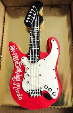 a red and white guitar shaped cake in a box