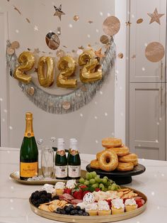 a table topped with lots of pastries and bottles of champagne next to a banner