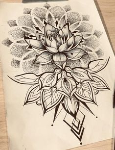 a black and white drawing of a flower on top of a piece of paper next to a pen