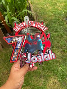 someone holding up a happy birthday sign in front of some plants and grass with the number seven on it