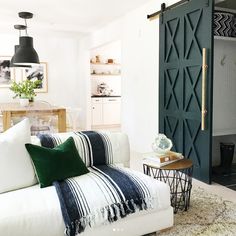 a living room with a white couch and green accents on the walls, along with an open sliding door