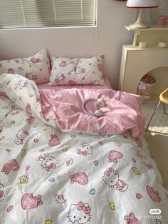 a bed with hello kitty sheets and pink comforter on top of it next to a window