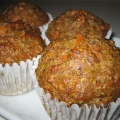 three carrot muffins sitting on top of a white plate next to each other