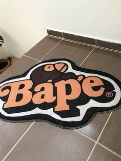 a sign that says bape on the floor in front of a potted plant