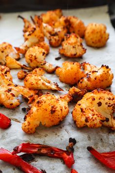 roasted cauliflower and peppers on a sheet of parchment paper with seasoning sprinkled over them