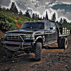 a black truck parked on the side of a dirt road