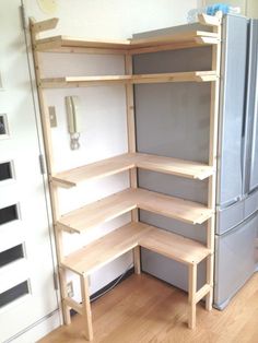 a refrigerator and shelves in a room with wooden floors, white walls and wood flooring