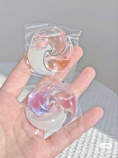 a hand holding two small plastic objects in it's palm, one is pink and the other is white