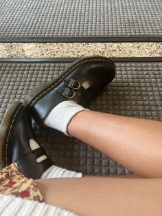 a person wearing black shoes and socks with white socks on their feet, sitting on a carpeted floor