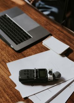 an old cell phone sitting on top of a desk next to a laptop computer and papers