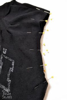 the back of a black t - shirt with yellow pins on it