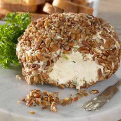 a bagel covered in nuts sitting on top of a white plate next to bread