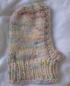 a knitted mitt laying on top of a white sheet