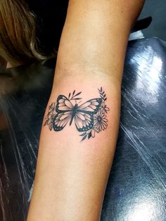 a woman's arm with a butterfly and flowers tattoo on the left side of her arm