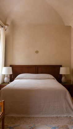 a bed sitting in a bedroom next to two lamps on either side of the bed