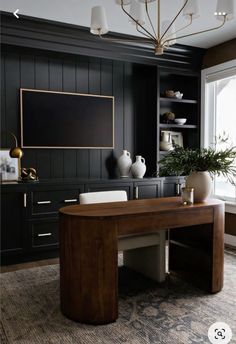 a large wooden desk sitting in front of a window next to a potted plant