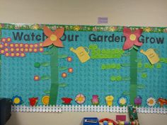 a classroom bulletin board with flowers and watering can on the bottom, which reads watch our garden grow