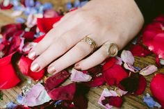 a woman's hand with two wedding rings on top of rose petals