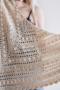 a woman is wearing a crocheted shawl