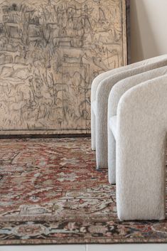 three white chairs sitting next to each other on top of a carpeted floor in front of a painting