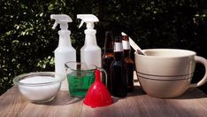 several bottles and containers are sitting on a table with soap, vinegar, and other items