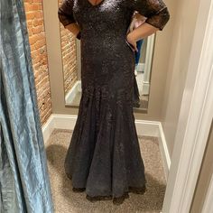 a woman taking a selfie in front of a mirror wearing a black dress with sequins