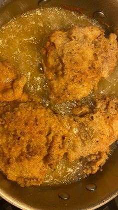 two pieces of fried chicken cooking in a pan