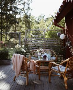 an outdoor table and chairs on a deck with flowers in the vases next to it