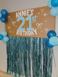 a 21st birthday sign with blue balloons and streamers hanging from it's side