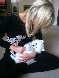 a woman is holding a small white dog