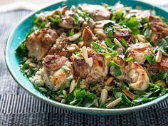 a blue bowl filled with meat and vegetables on top of a bed of green leaves