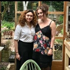 two women standing next to each other in a greenhouse