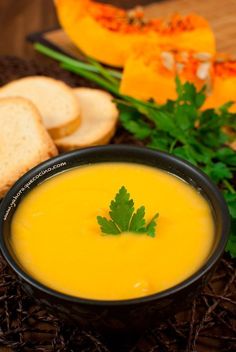 a bowl of soup with bread and parsley on the side, next to it