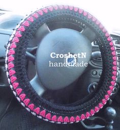 a car steering wheel cover with pink and black trim