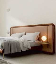 a bed with white sheets and pillows in a bedroom next to a wall mounted lamp