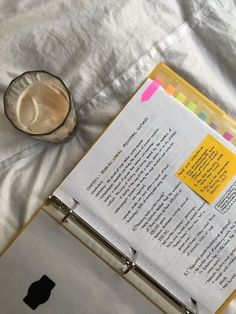 an open book sitting on top of a bed next to a cup and saucer