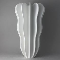 a large white vase sitting on top of a table next to a gray wall and floor