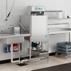 an industrial kitchen with sink, counter and trash can on the floor next to it