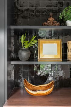 a wooden bowl sitting on top of a shelf next to other vases and potted plants