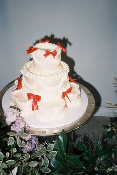 a three tiered wedding cake with red bows