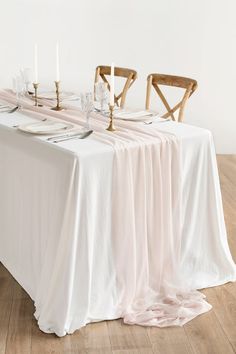 the table is set with white linens and candles