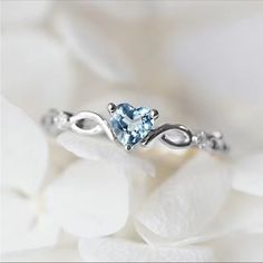 a white gold ring with an aqua blue topazte stone in the center on a flower