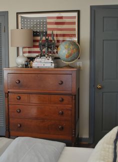 a bedroom with an american flag on the wall and a chest of drawers in front of it