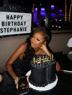 a woman sitting in front of a birthday cake